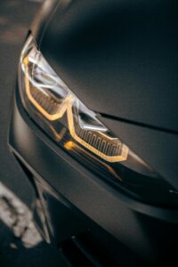 Illuminated car headlight close-up taken in San Jose, showcasing automotive elegance.