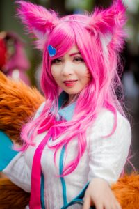 Colorful cosplay portrait of a young woman in pink wig and animal ears, exuding joy and creativity.