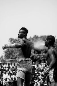 Black men participating in a street boxing match with an audience.