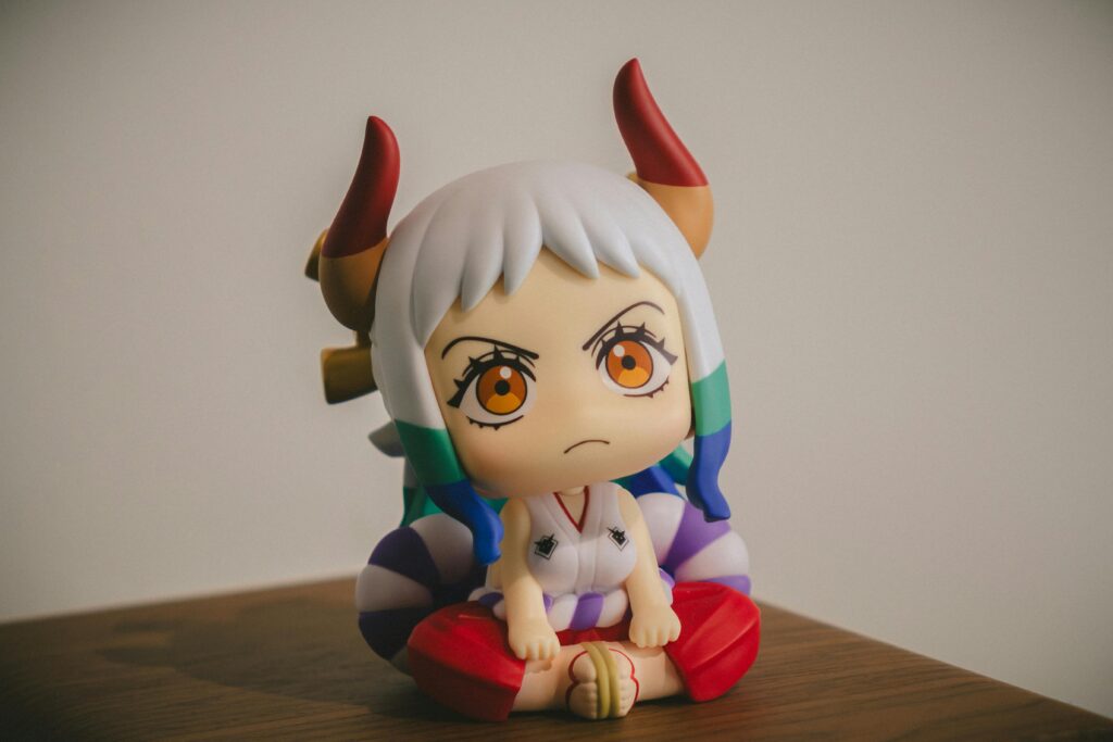 Close-up of a colorful anime figurine with horns, sitting on a wooden surface.