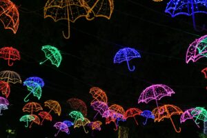Vibrant neon-lit umbrellas hanging in an outdoor night display.