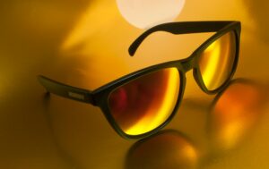 Close-up of fashionable sunglasses with yellow reflective lenses on a vibrant background.