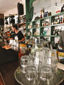 Warm bar setting with glassware and attentive bartender.