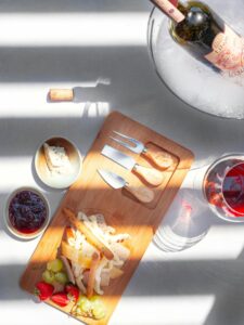 Elegant cheese platter with wine and fruits, perfect for a classy evening.