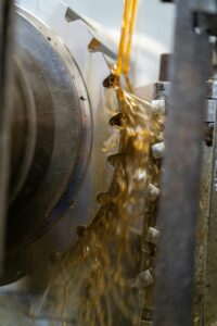 Close-up of a gear being lubricated with oil during manufacturing.