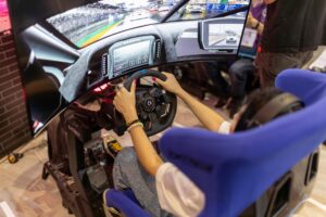 Person using a realistic VR racing simulator at a gaming event, focused on the immersive experience.