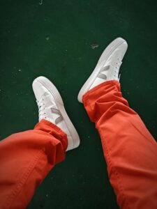 Stylish Veja sneakers paired with vibrant red pants against a green floor.
