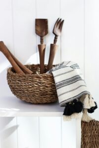 Stylish wooden utensils in a woven basket with striped cloth, rustic kitchen decor.