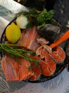 Fresh salmon fillets with vegetables and herbs on a colorful plate, ready for cooking.