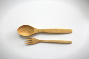 Close-up of a wooden spoon and fork on a clean white background, perfect for kitchen themes.