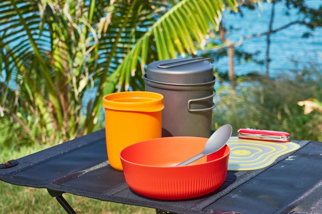 Minimalist camping cookware on a folding table with a tropical view in Trat, Thailand.