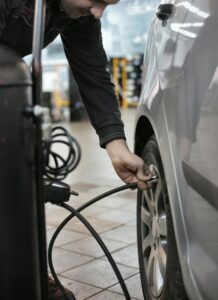 Mechanic adjusting tire pressure of a vehicle in an indoor automotive service center.