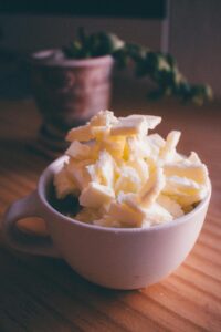 A pile of butter curls stacked in a white ceramic mug on a wooden table.