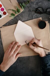 Artistic handwriting on an envelope using a fountain pen, surrounded by art supplies.