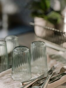 Close-up of clean glassware and utensils drying in a cozy kitchen setting, emphasizing home cleanliness.