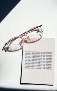 Eyeglasses resting on a motivational note, captured in a minimalist style with soft lighting.