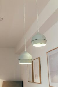 A minimalist interior featuring modern white pendant lamps and framed artworks.
