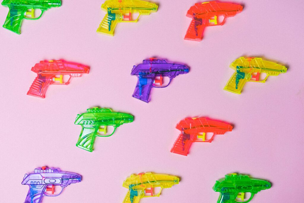 Top view of various multicolored toys for fight arranged on pink background as representation of game