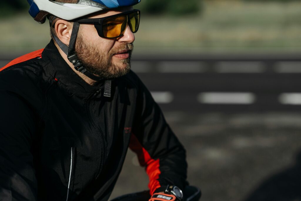 Side profile of a cyclist wearing protective gear and sunglasses on a sunny day.