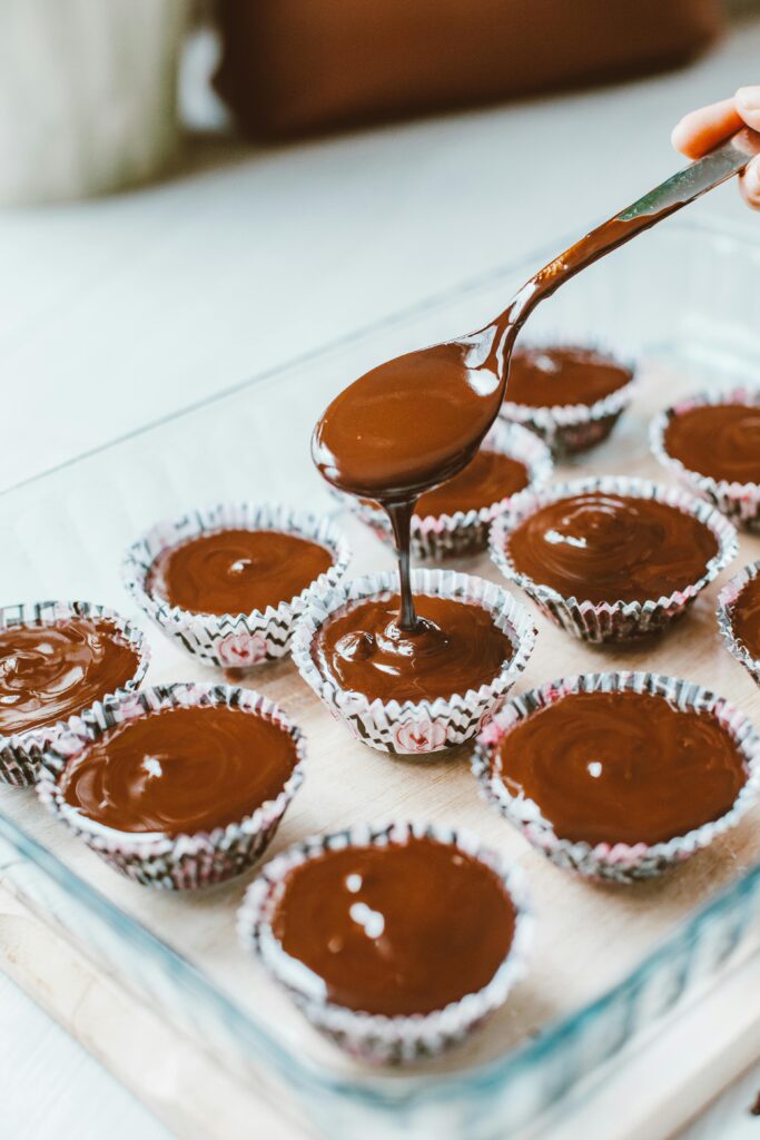 Delicious chocolate batter being poured into cupcake moulds for baking.