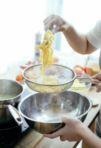 A person preparing fresh homemade pasta with steam in a modern kitchen setting.