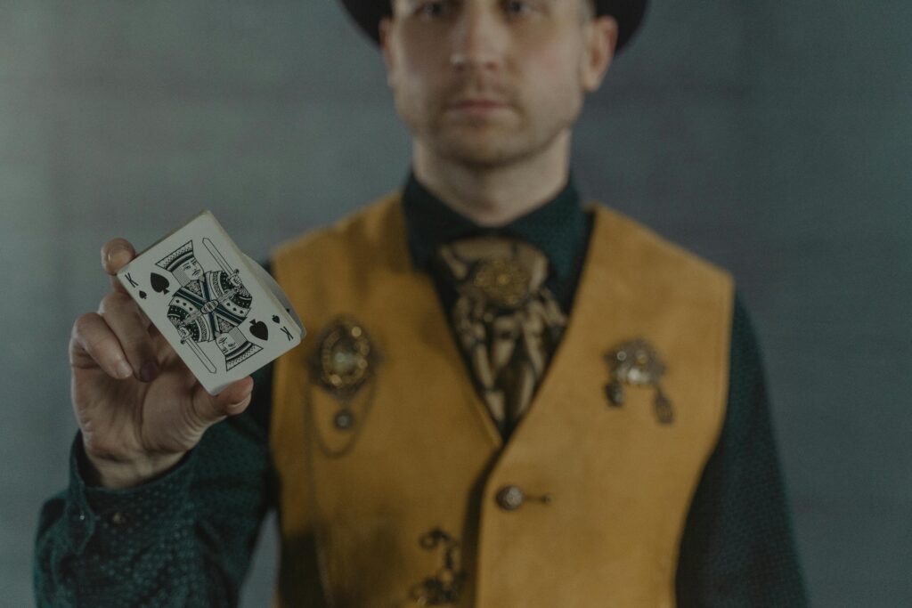 A magician displays the King of Spades card, creating intrigue and focus in a dimly lit scene.