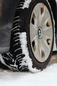 Close-up of a tire with snow, highlighting the wheel and snowy tread.