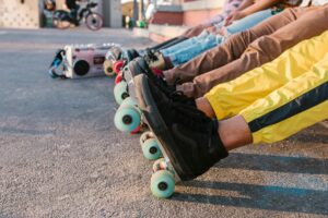 A group of friends relaxing in line with vibrant roller skates at an outdoor skatepark.