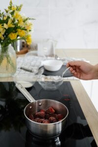 Preparing a delicious strawberry dessert on a modern stovetop with flower decor.