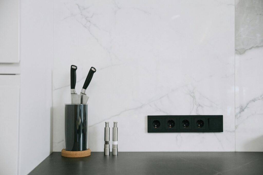Modern kitchen with marble backsplash, knife holder, and power outlets.