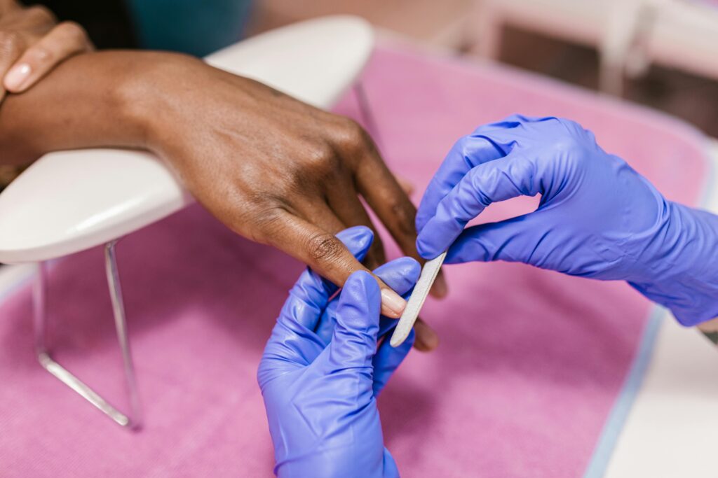 Close-up of hand receiving a manicure with latex gloves, showcasing precision and care.