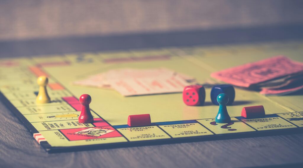 A close-up of a Monopoly board game with pieces and dice scattered around.
