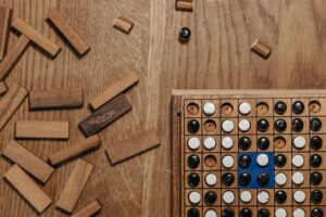 Flat lay of a strategy board game with wooden pieces and a game board on a wooden table.
