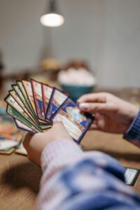 Close-up of hands holding a fan of playing cards indoors with warm lighting.