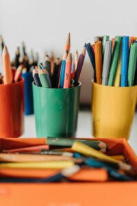 Vibrant pencils and pens arranged in colorful cups, ideal for educational settings.