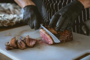 Chef slicing a perfectly cooked steak on a chopping board, showcasing juicy and delicious meat.