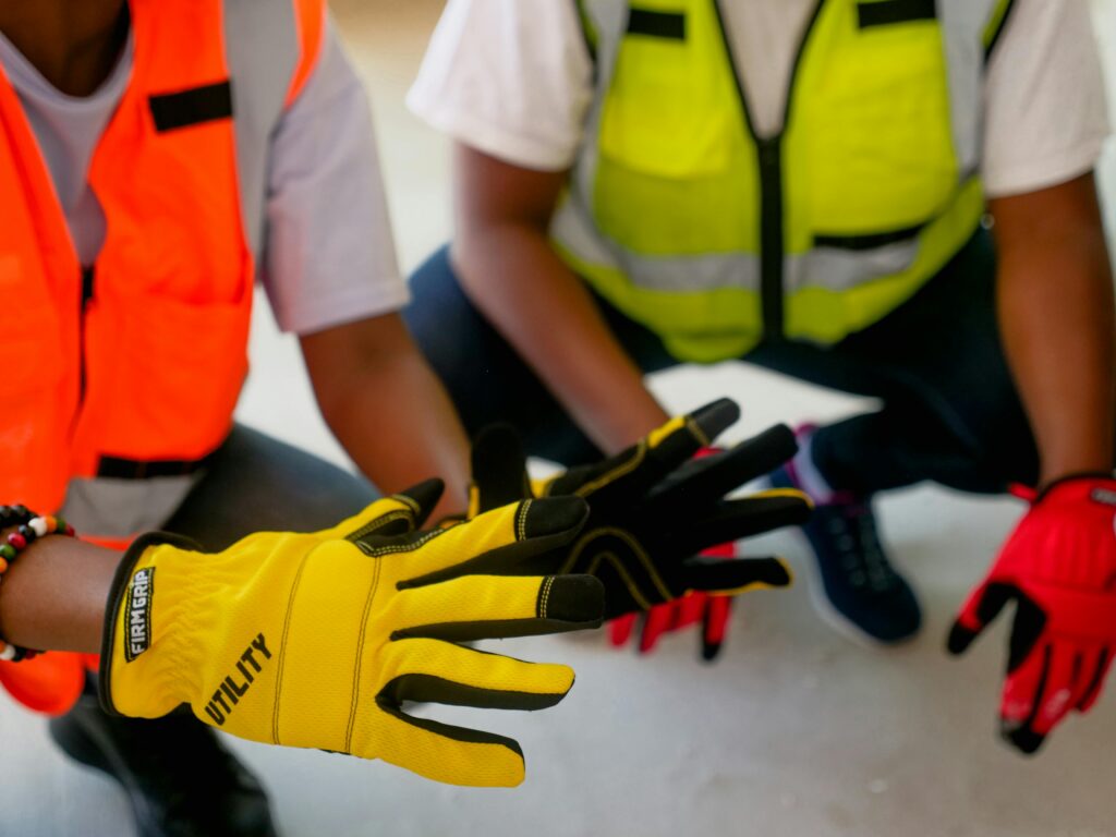 Close-up of two workers wearing protective gloves and reflective vests, focused on safety equipment.