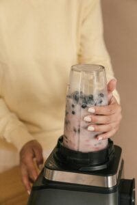 A woman blending a nutritious berry smoothie in a kitchen setting.