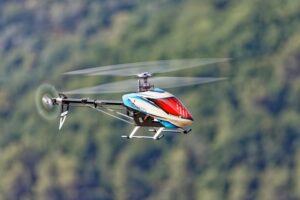Close-up of a remote-controlled helicopter flying against a blurred natural background.