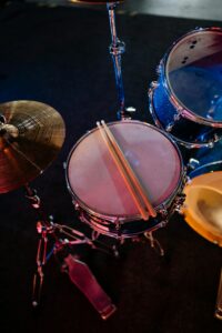 Dynamic close-up of a drum set featuring drumsticks over a snare drum with cymbals.
