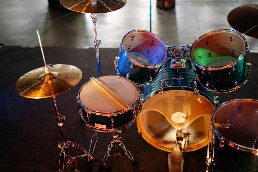 A vibrant drum set with colorful reflections on stage, ready for a performance.