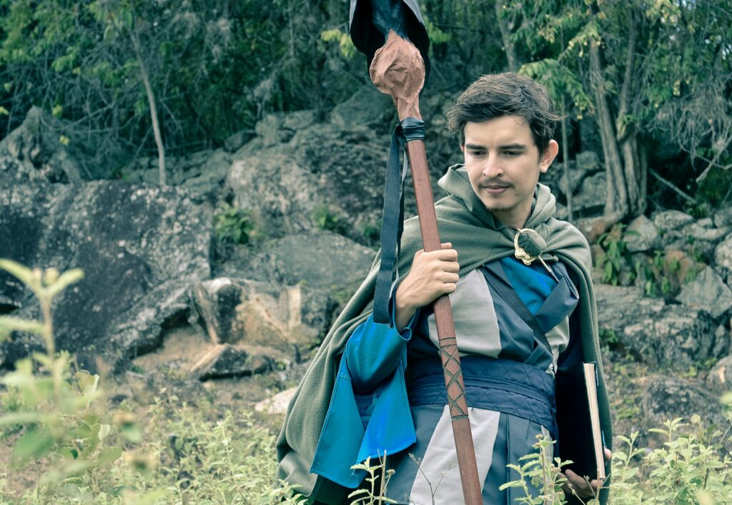 Man wearing medieval cosplay costume holding staff in a forest setting in Colombia.