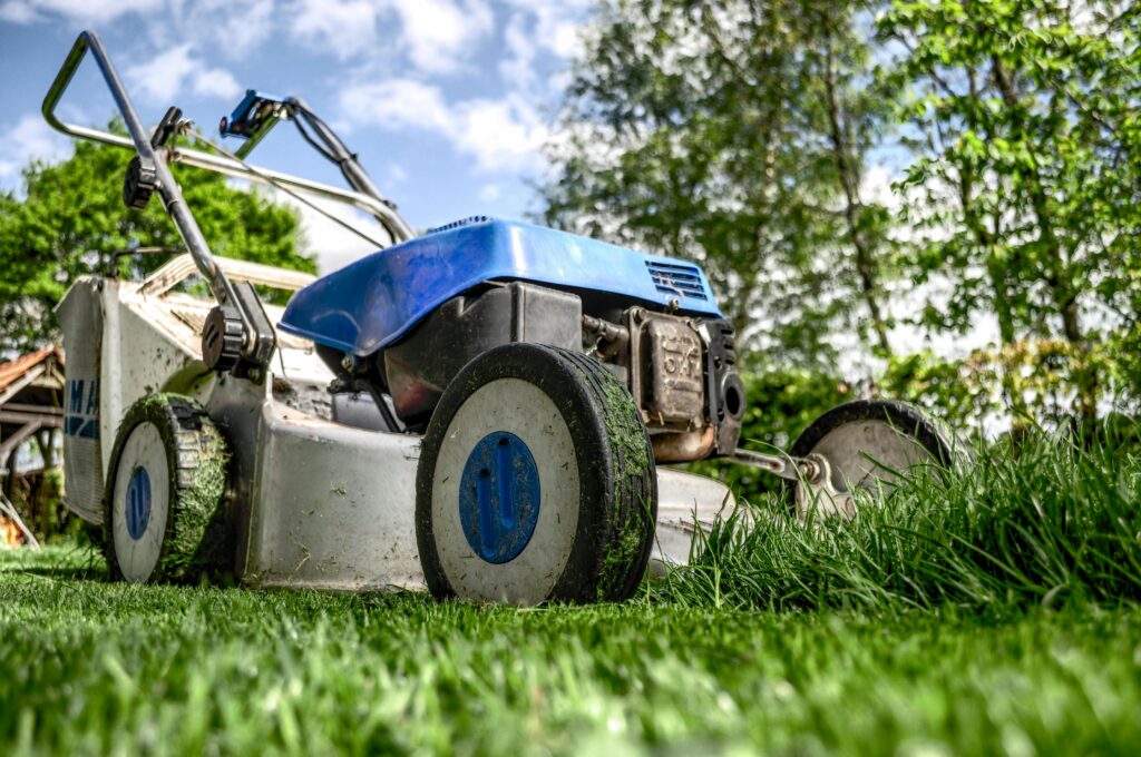 Close-up view of a lawn mower cutting grass in a garden on a sunny day.