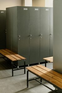 Spacious locker room featuring grey lockers and wooden benches, ideal for fitness centers.