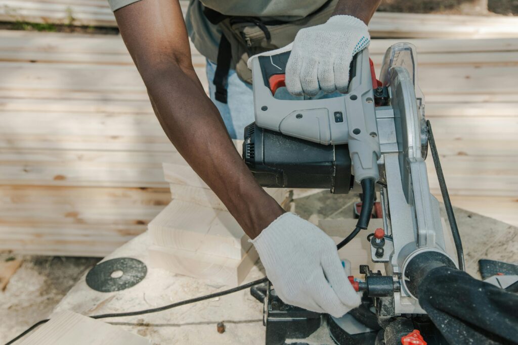 A worker uses a circular saw to cut wood outdoors, showcasing skillful woodwork techniques.